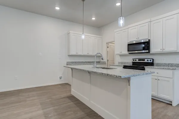 a kitchen with stainless steel appliances granite countertop a stove a sink and a microwave