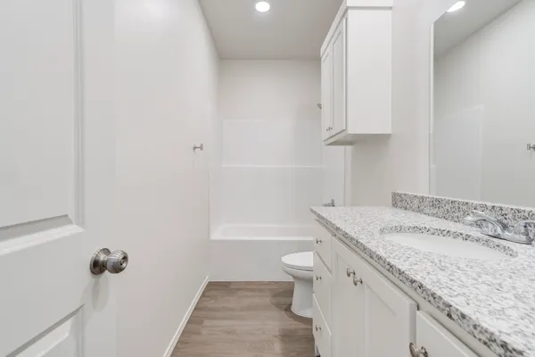 a bathroom with a granite countertop sink a toilet and bathtub