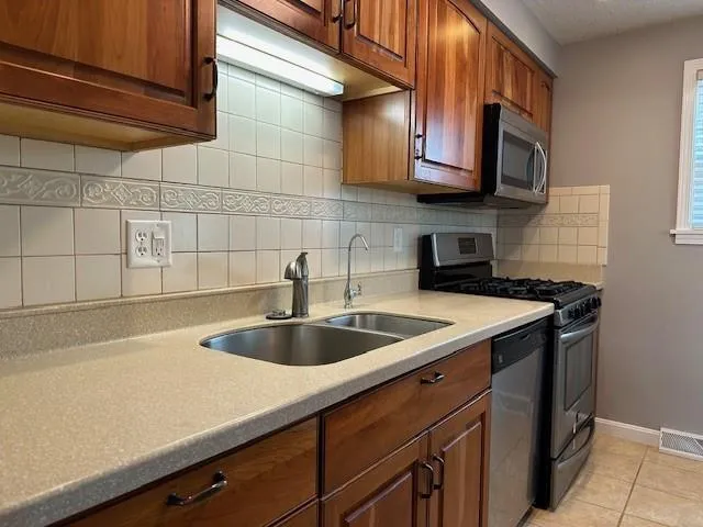 a kitchen with stainless steel appliances granite countertop a sink a stove and cabinets
