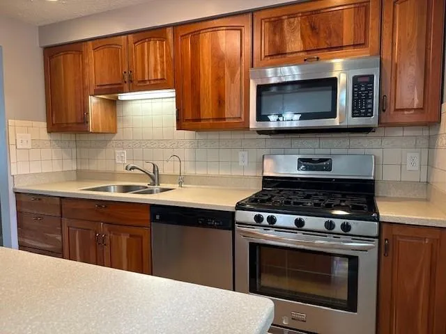a kitchen with stainless steel appliances granite countertop a stove microwave and sink