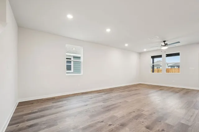 an empty room with wooden floor and windows