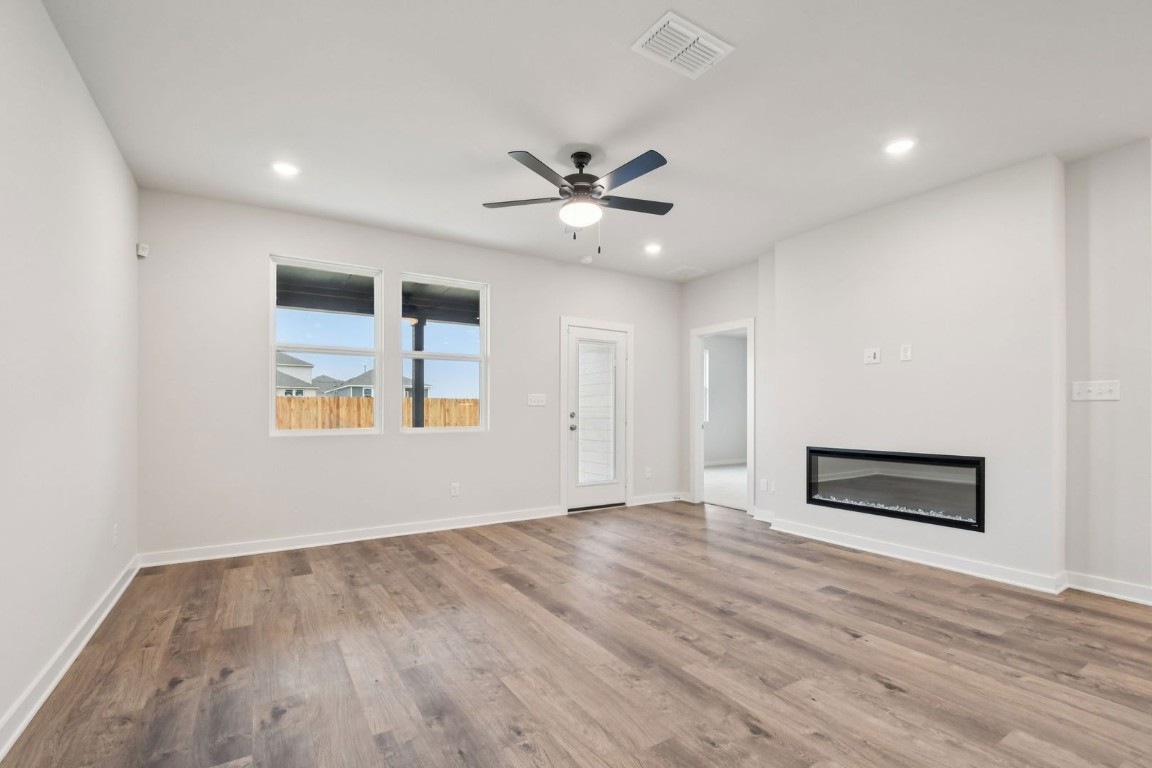 13417 Derby Ride Drive Buda, TX 78610 - Photo 16 of 38 an empty room with wooden floor chandelier fan and windows