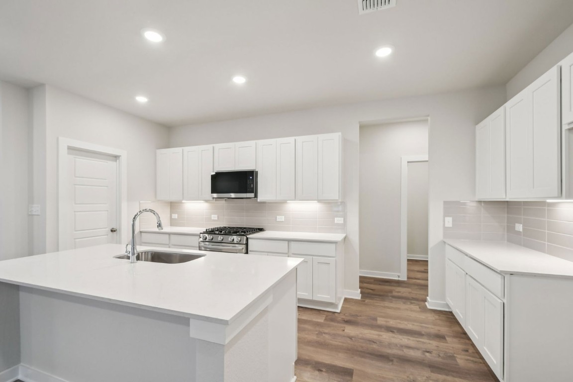 13417 Derby Ride Drive Buda, TX 78610 - Photo 6 of 38 a kitchen with stainless steel appliances a sink stove and cabinets