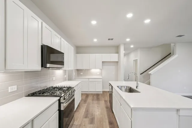 a kitchen that has a sink a stove and white cabinets