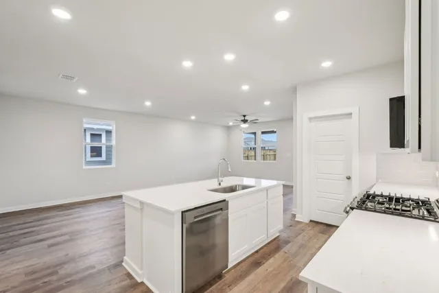 a kitchen with a sink a stove and white cabinets