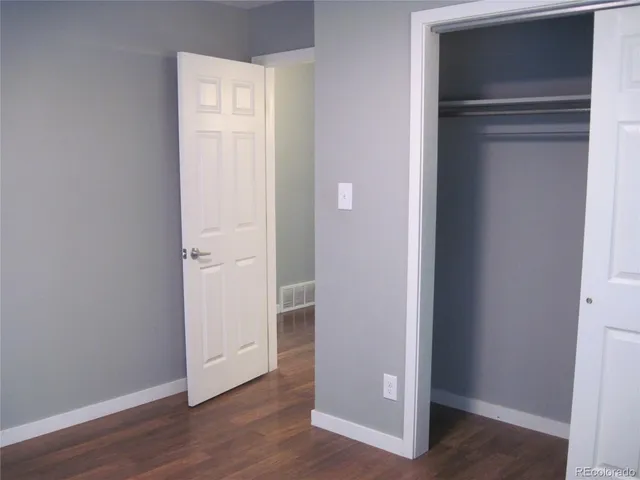 a view of an empty room with wooden floor & closet