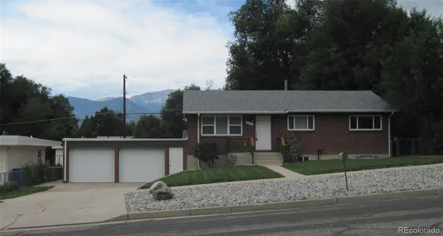a front view of a house with garage and plants