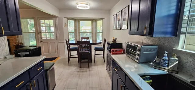 a kitchen with stainless steel appliances granite countertop a stove top oven a sink a dining table and chairs with wooden floor