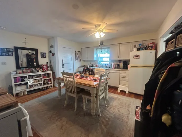 a kitchen with stainless steel appliances kitchen island granite countertop a sink dishwasher a stove a refrigerator a dining table and chairs with wooden floor