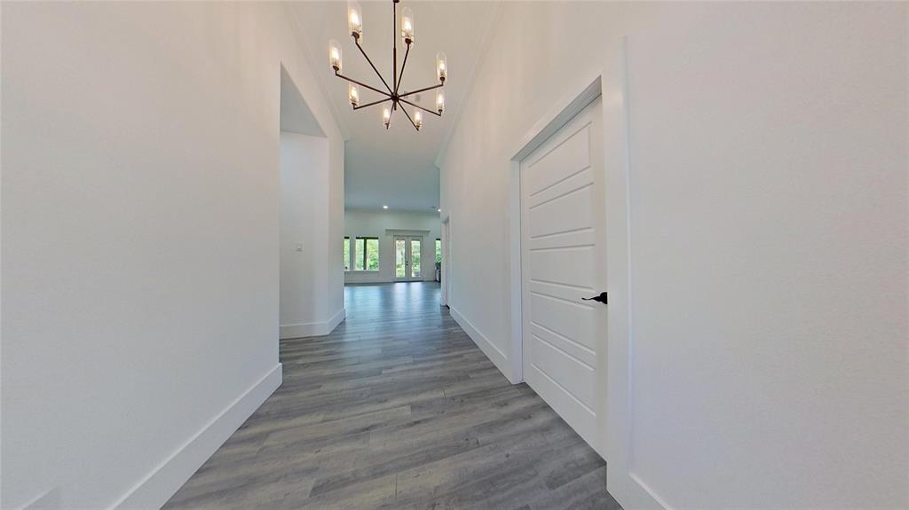 3248 North Cardinal Road Azle, TX 76020 - Photo 7 of 29 Hallway featuring light gray wood-finish flooring, white baseboards, and a contemporary linear chandelier with multiple light sources