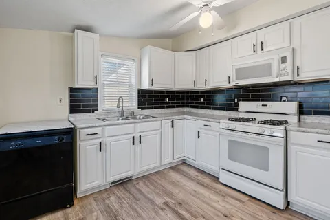 a kitchen with granite countertop white cabinets and white appliances