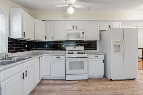 a kitchen with white cabinets and white appliances