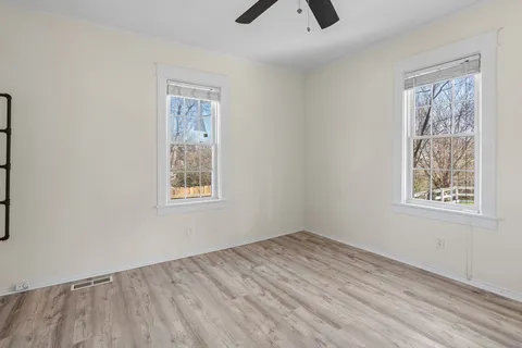 a view of an empty room with window and wooden floor