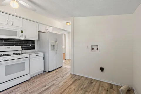 a view of a kitchen with refrigerator stove and wooden floor