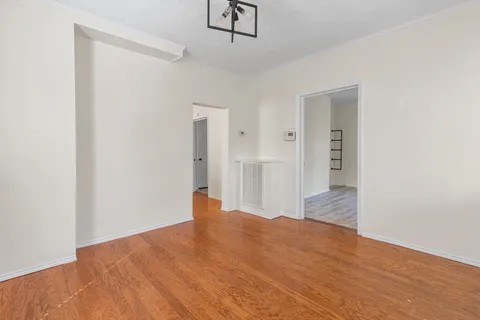 a view of empty room with wooden floor and ceiling fan