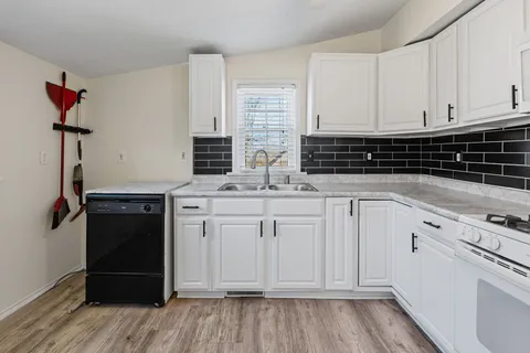 a kitchen with granite countertop white cabinets and black appliances