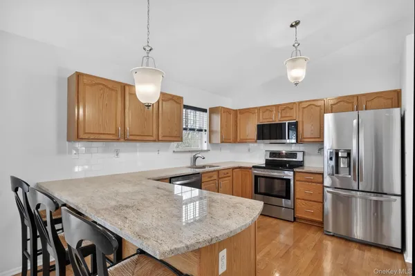 a kitchen with stainless steel appliances granite countertop a sink a stove a refrigerator cabinets and a dining table