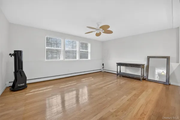 a view of an empty room with a window and wooden floor