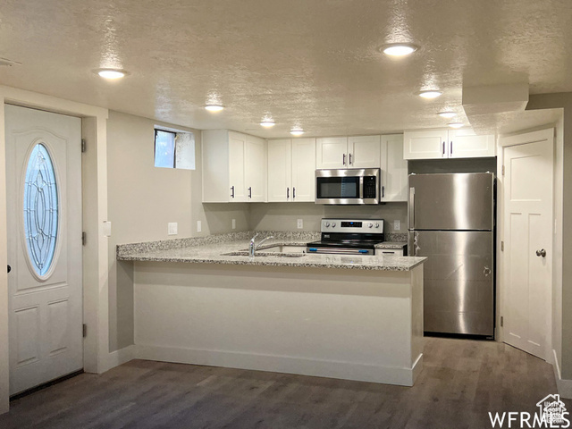 702 North 100 West Logan, UT 84321 - Photo 45 of 58 Kitchen with stainless steel appliances, a textured ceiling, a sink, white cabinets, and wood finished floors