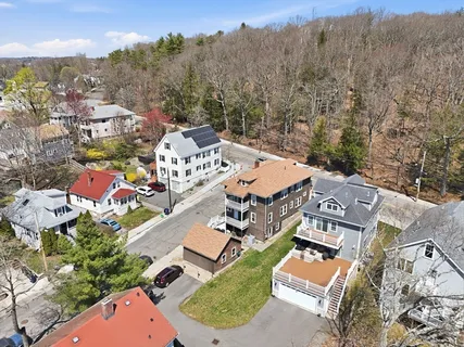 an aerial view of residential house with outdoor space and trees all around