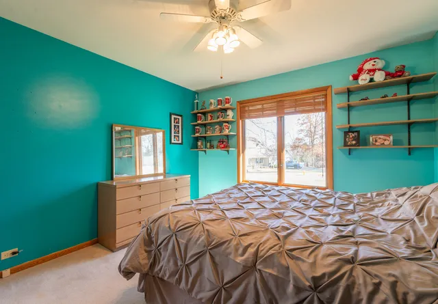 a bed sitting in a bedroom next to a window with a bookshelf