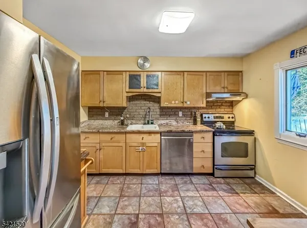 a kitchen with stainless steel appliances granite countertop a stove a sink and a refrigerator