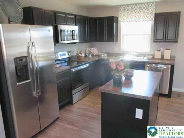 a kitchen with stainless steel appliances granite countertop a refrigerator a sink a stove with wooden cabinets