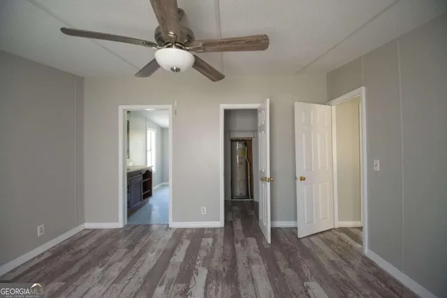 a view of an empty room with wooden floor and a ceiling fan