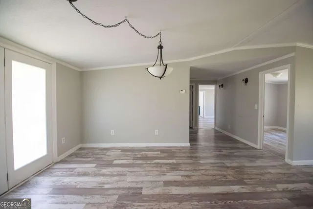 a view of an empty room with wooden floor and windows
