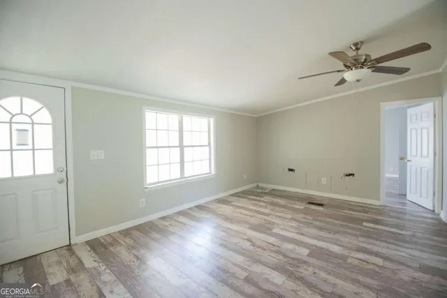 a view of an empty room with wooden floor and a window