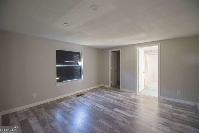 a view of an empty room with a window and wooden floor