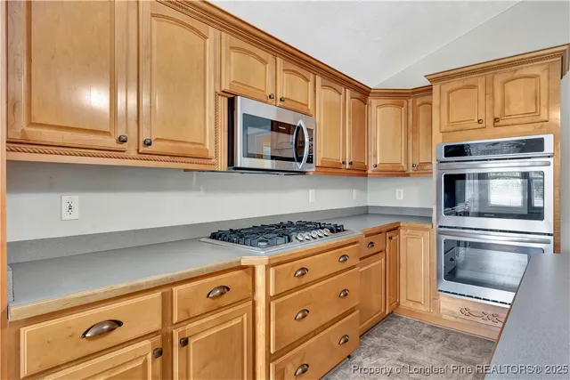 a kitchen with stainless steel appliances granite countertop a sink a stove cabinets and living room view