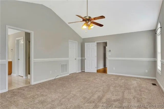 an empty room with closet and a chandelier fan