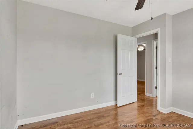 a view of an empty room with window and wooden floor
