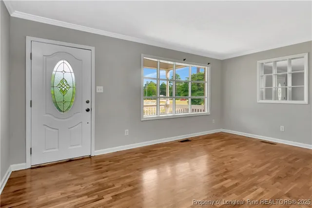 an empty room with wooden floor and windows