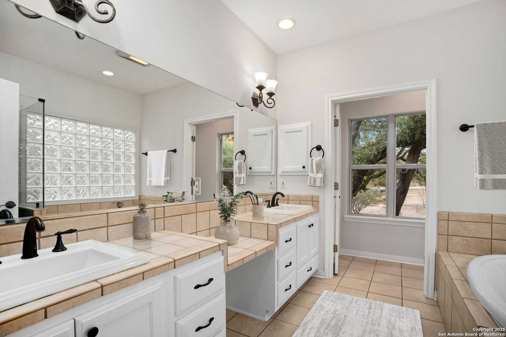 1245 Phantom Rider Trail Spring Branch, TX 78070 - Photo 7 of 48 a spacious bathroom with a double vanity sink a mirror a bathtub and window