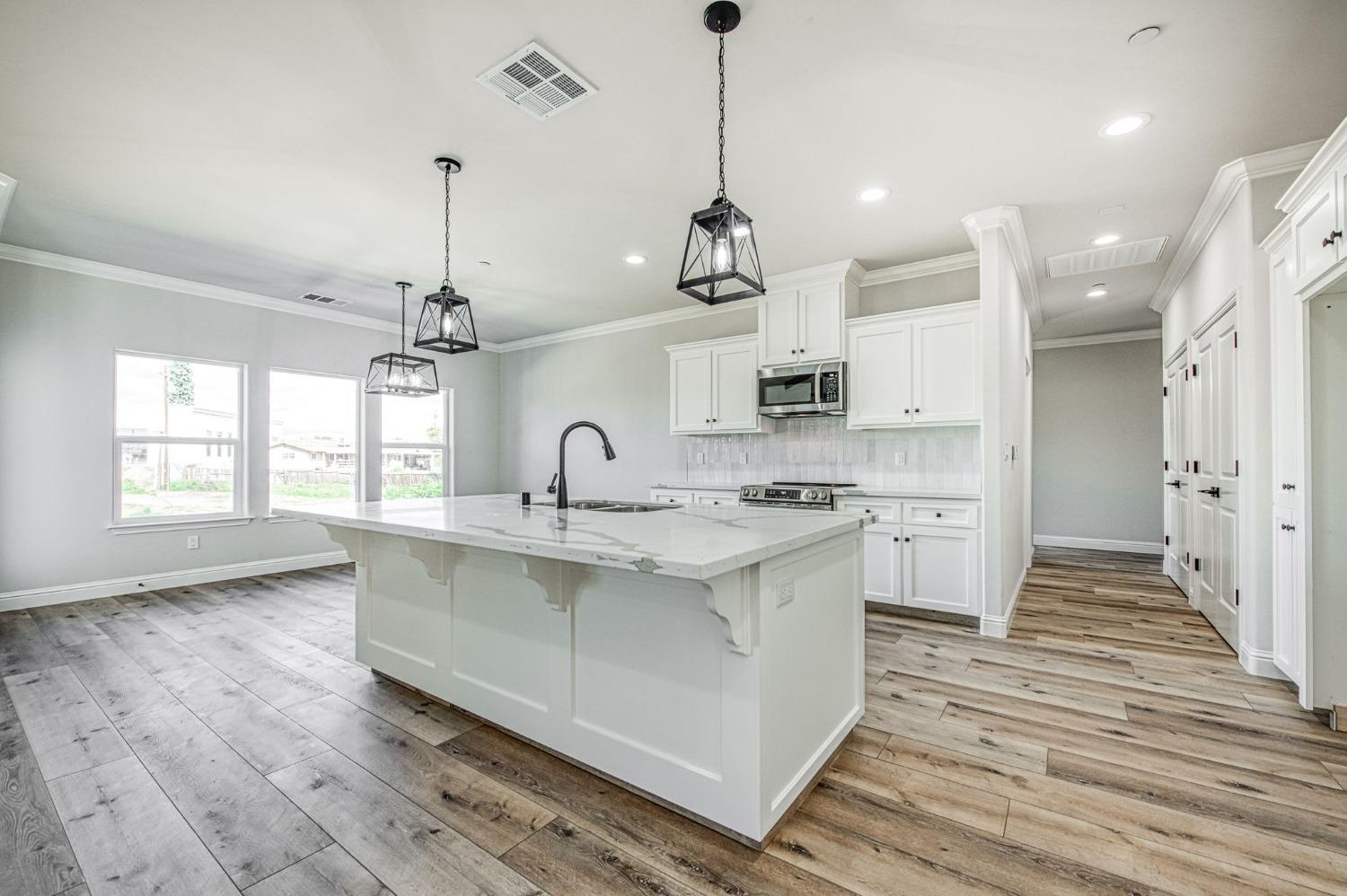11271 Mountain View Drive Madera, CA 93636 - Photo 4 of 73 a large kitchen with kitchen island a stove a sink a center island and wooden floor