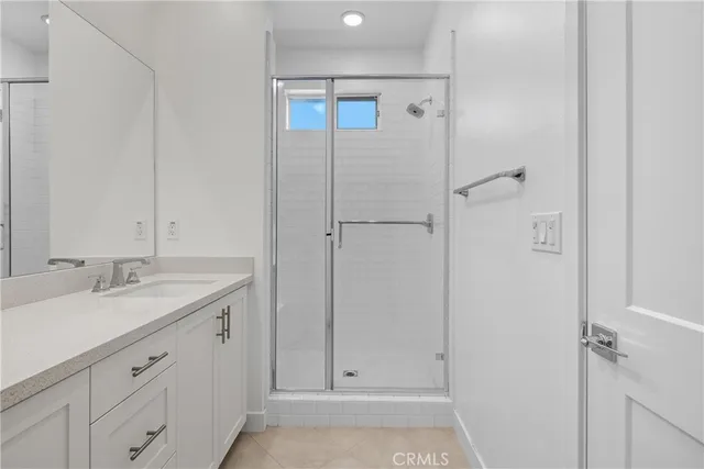 a bathroom with a granite countertop sink two mirror and shower