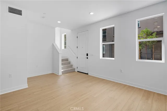 a view of an empty room with wooden floor and windows