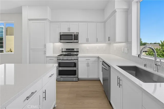 a kitchen with granite countertop a sink stainless steel appliances and cabinets