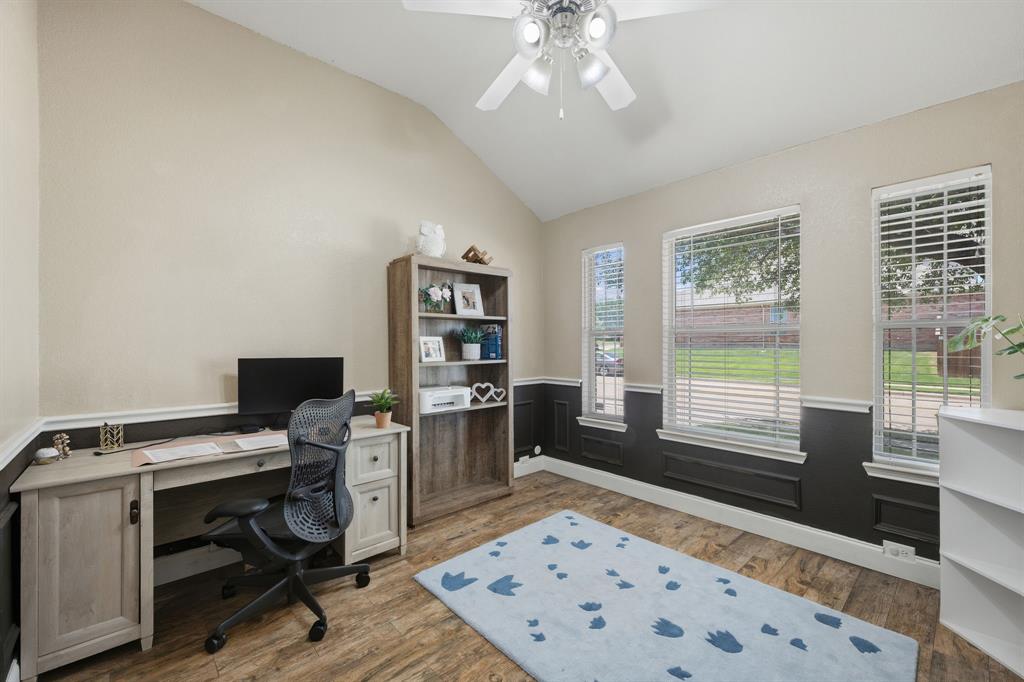 14152 Rodeo Daze Drive Fort Worth, TX 76052 - Photo 12 of 20 Vaulted ceiling room featuring wood-finish flooring, three windows with white blinds, and two-tone walls with dark wainscoting