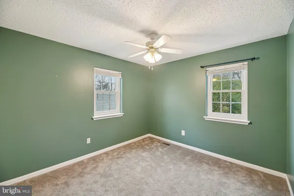 an empty room with a window and ceiling fan
