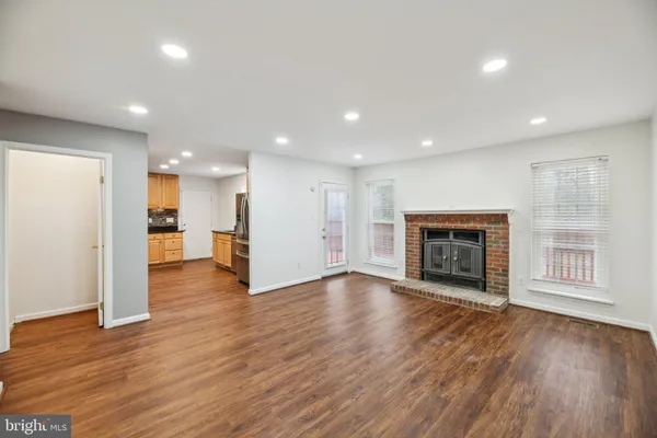 a view of an empty room with wooden floor and a fireplace