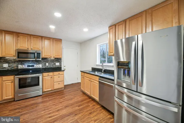 a kitchen with granite countertop a stove a sink and a refrigerator