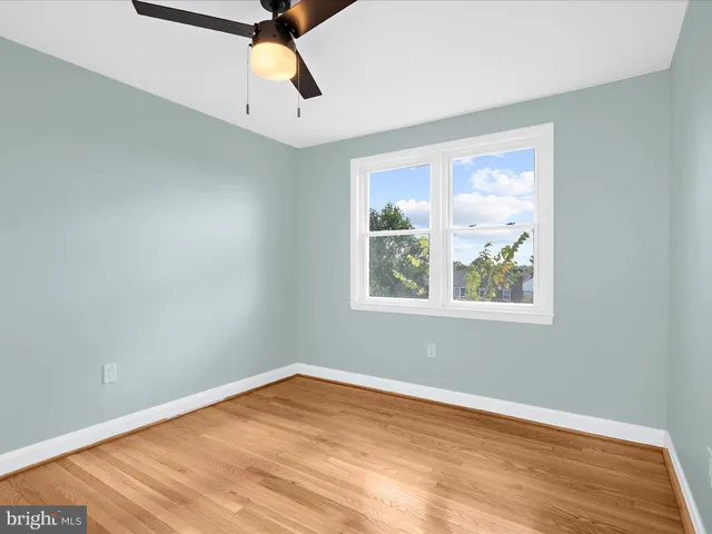 a view of empty room with wooden floor and window