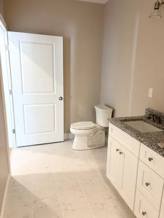 a bathroom with a granite countertop sink and a toilet