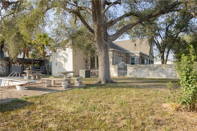 a view of the house with a large tree and a yard