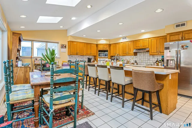 a kitchen with stainless steel appliances lots of white furniture a dining table and chairs
