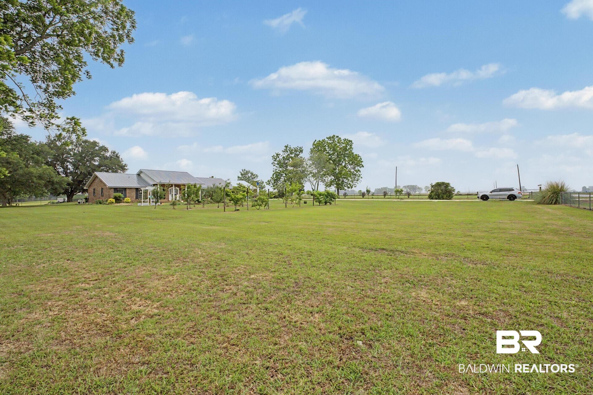 3791 Robinsonville Road Atmore, AL 36502 - Photo 7 of 47 Expansive green lawn with a distant single-story brick residence featuring a covered porch and mature trees