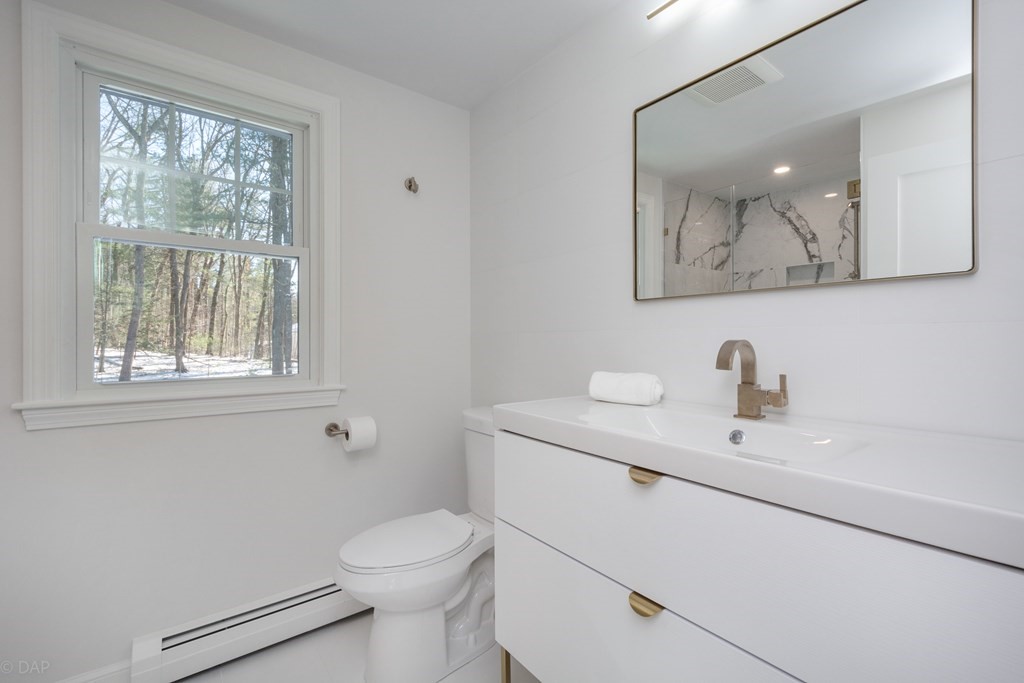 143 Hillcrest Road Concord, MA 01742 - Photo 24 of 42 a bathroom with a toilet a sink a mirror and a window